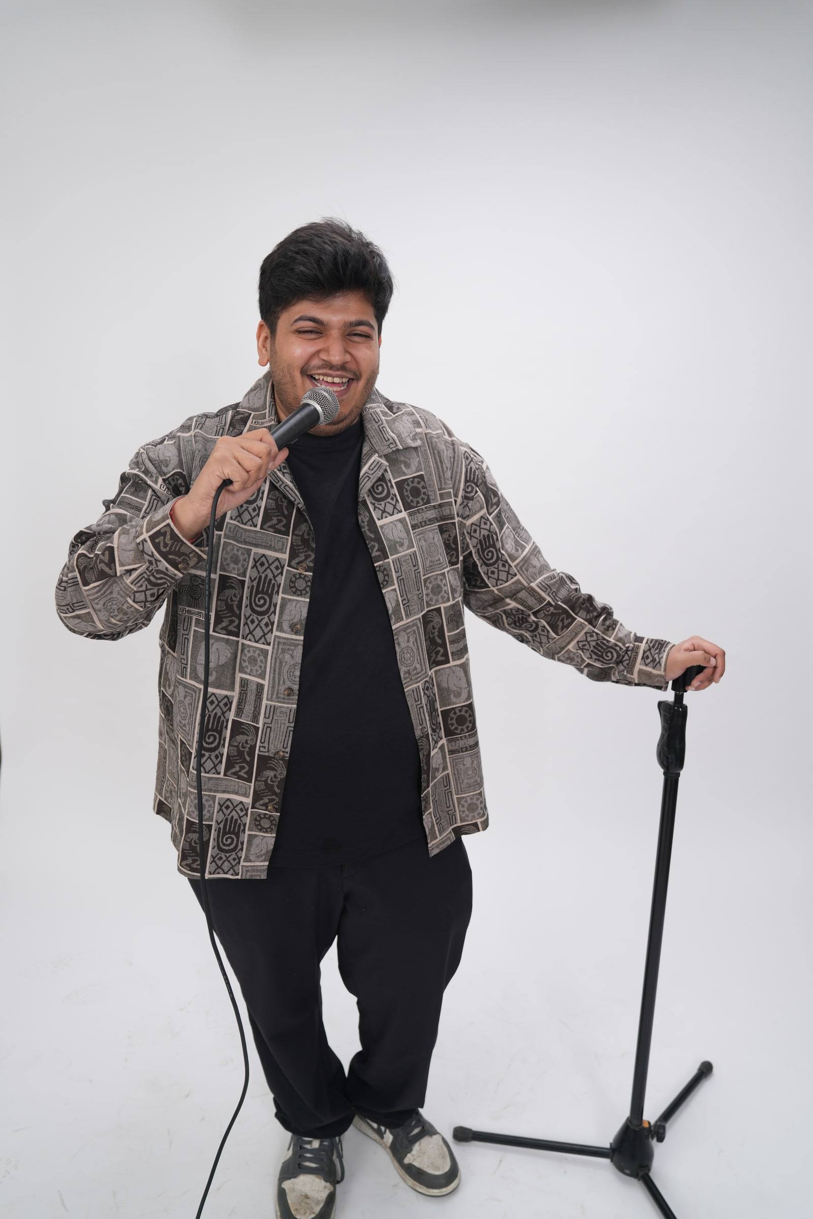 Kaustubh Agarwal leaning on a microphone stand, laughing