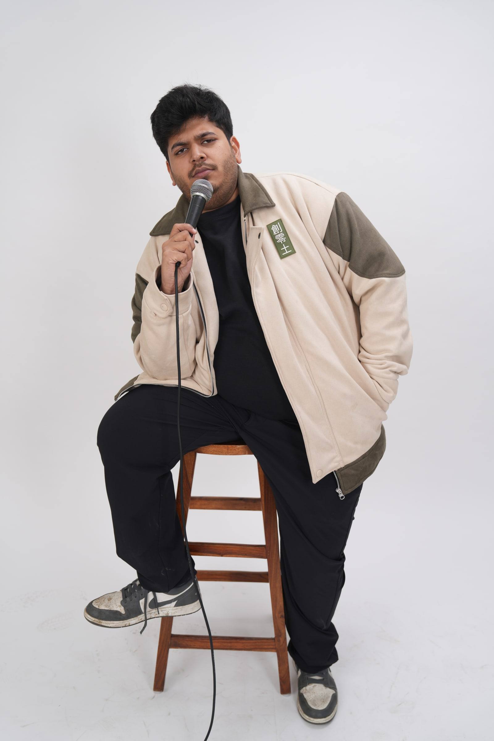 Kaustubh Agarwal sitting on a wooden stool with a microphone
