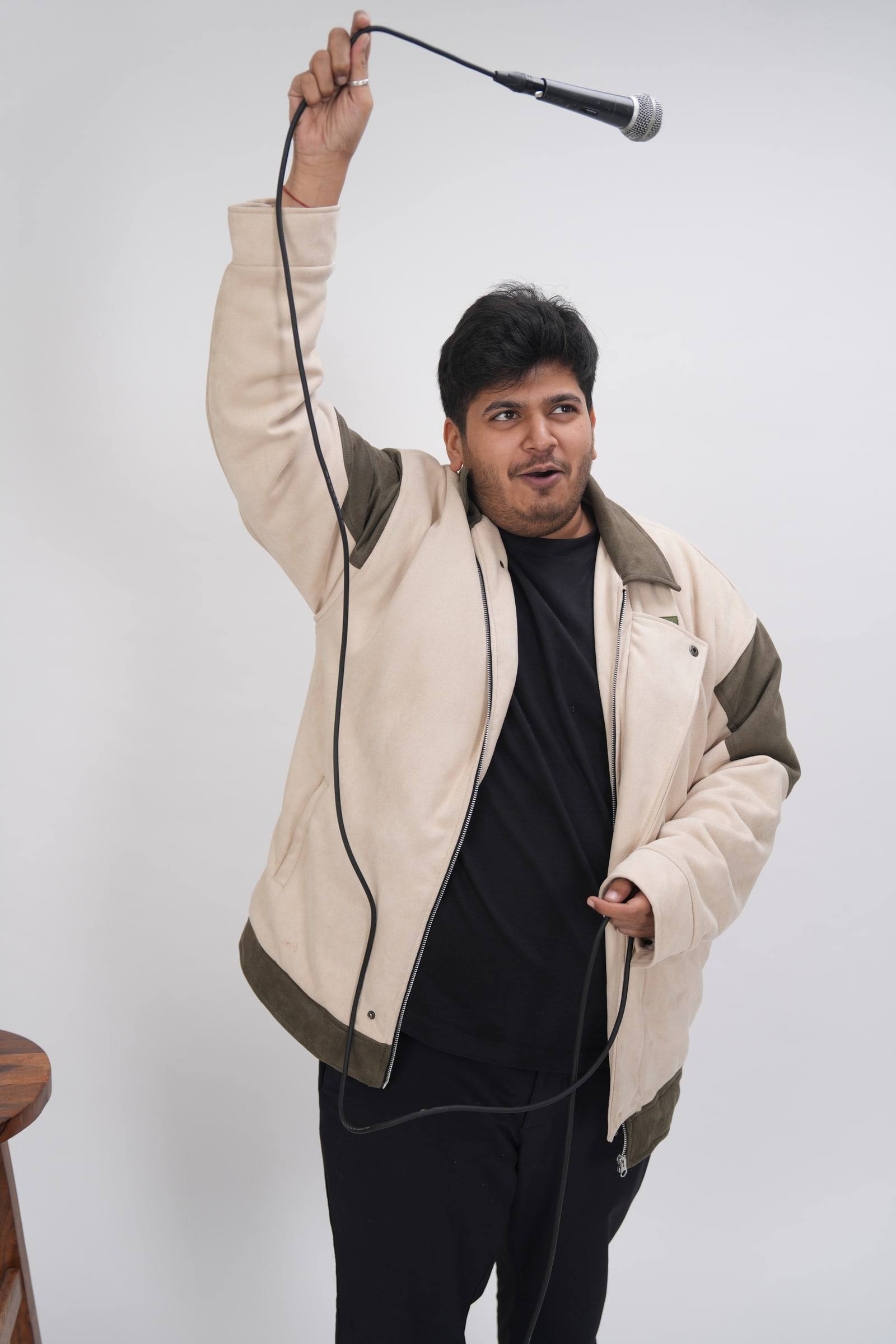 Kaustubh Agarwal holding a microphone high above his head by its cable