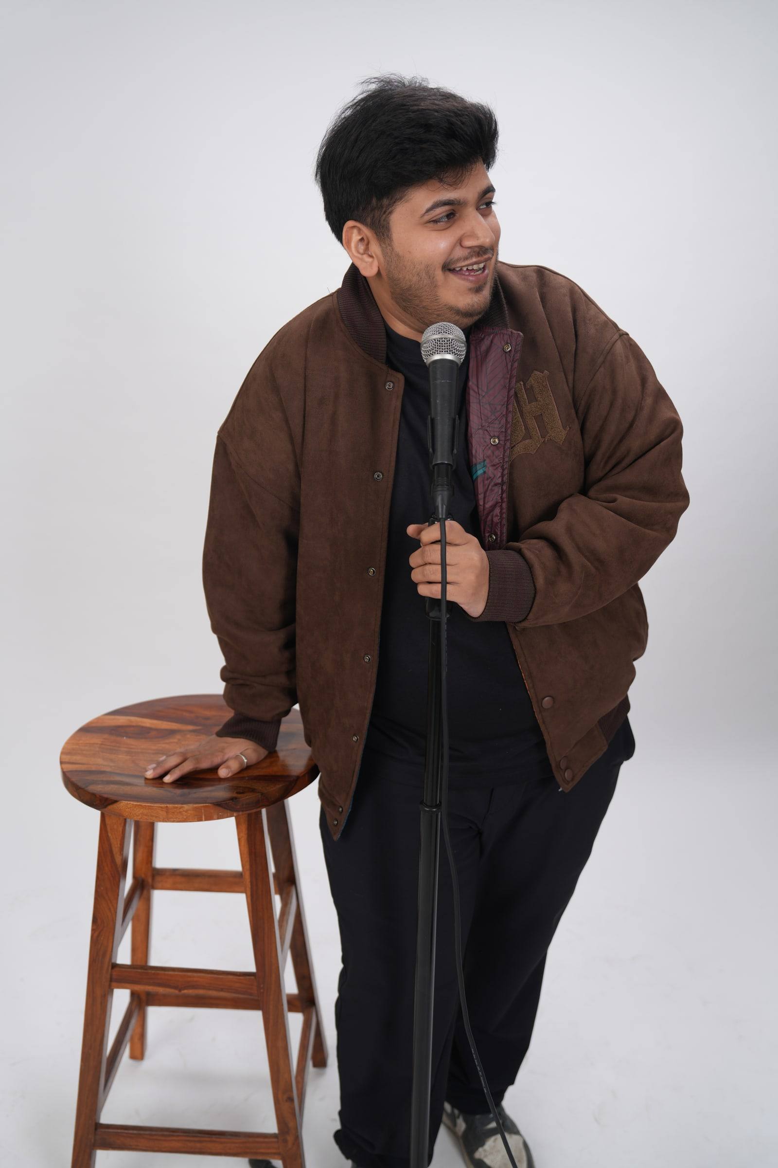 Kaustubh Agarwal standing beside a wooden stool, looking off to the side